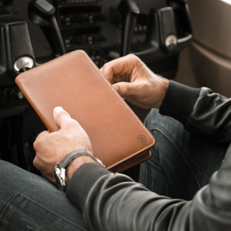 Large zip-around travel and passport organiser in clay leather by Jekyll & Hide, being opened by man